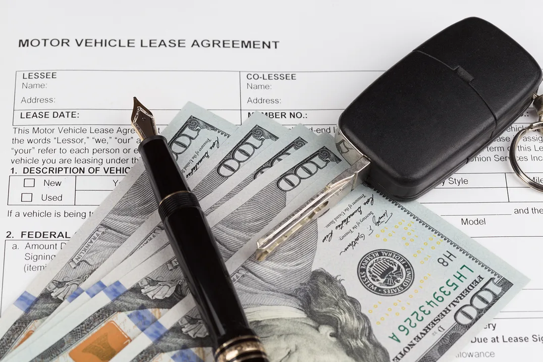 Motor vehicle lease agreement with cash, a pen and car keys